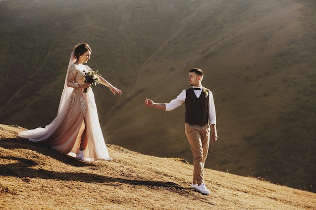 Elegante joven pareja se divierte posando en las hermosas montañas georgianas