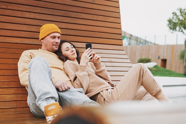 Elegante joven pareja familiar enamorada de hipsters usando el móvil en el parque