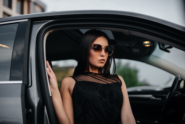 Elegante joven sentado en un coche de clase ejecutiva en un vestido negro. Moda y estilo empresarial