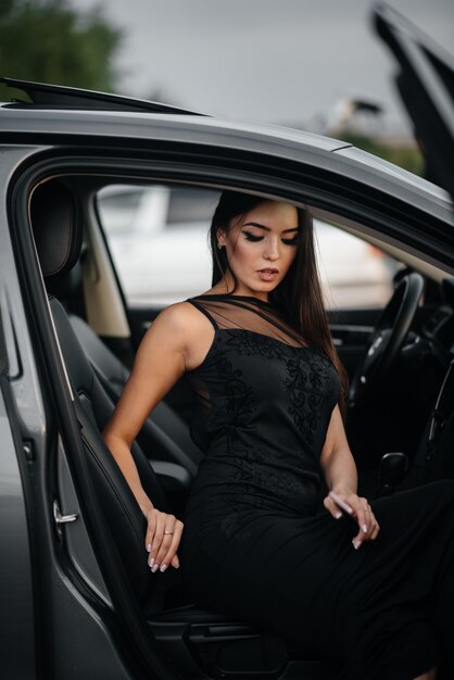 Elegante joven sentado en un coche de clase ejecutiva en un vestido negro. Moda y estilo empresarial