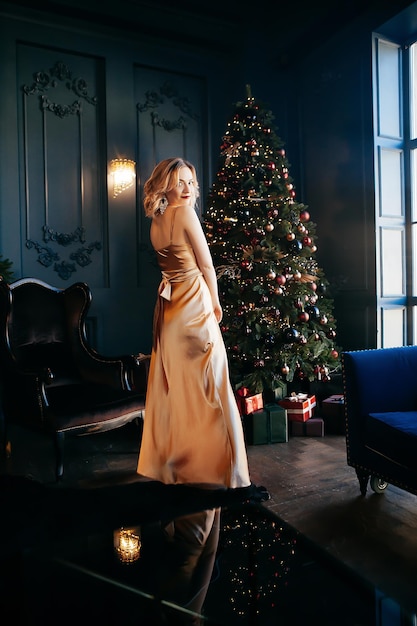 Elegante junge Frau in einem Kleid im Inneren eines Weihnachtsbaums