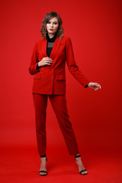 Elegante junge Frau in roter Anzugjacke Hose Hose schwarze Bluse auf Hintergrund Monochrom