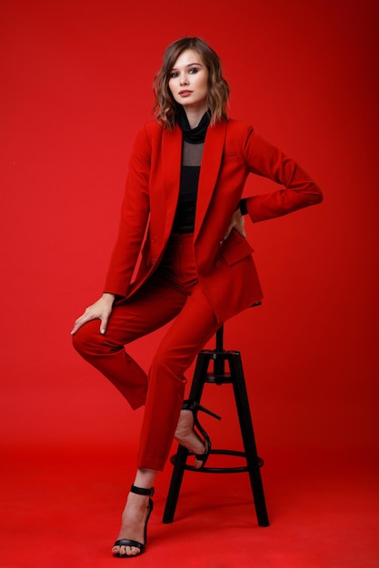Elegante junge Frau in roter Anzugjacke Hose Hose schwarze Bluse auf Hintergrund Monochrom