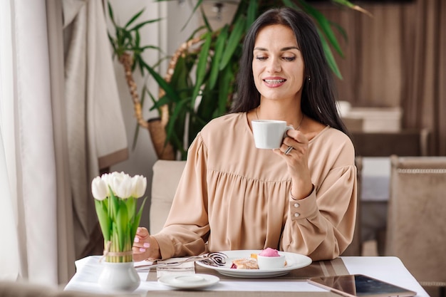 Elegante kaukasische Frau im Kleid isst leckeres süßes Dessert in der Cafeteria