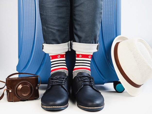 Elegante maleta, piernas de hombre y medias multicolores.