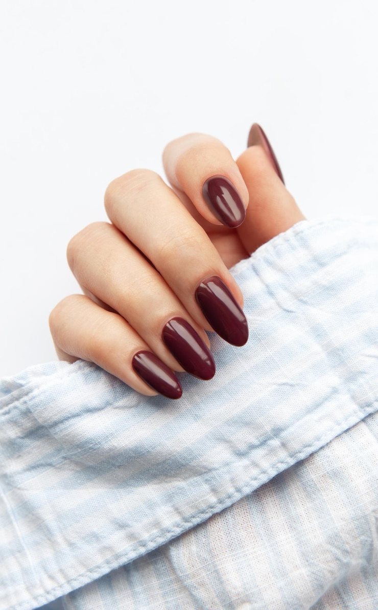 Foto elegante manicure vermelho escuro exibido na mão de uma mulher