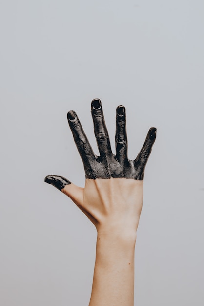 Elegante mano femenina bañada en pintura negra. Aislado. Gesto.