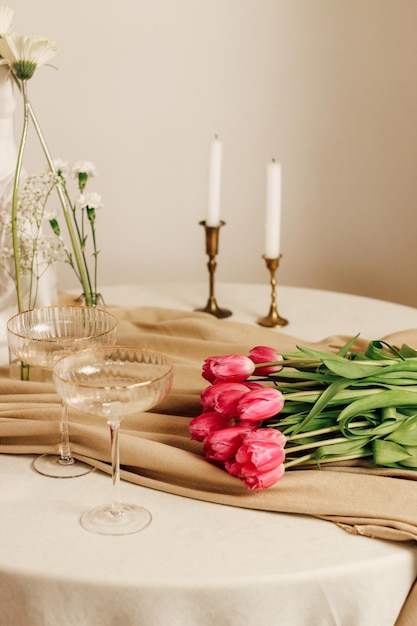 Elegante mesa romántica en el interior con gafas y un ramo de tulipanes