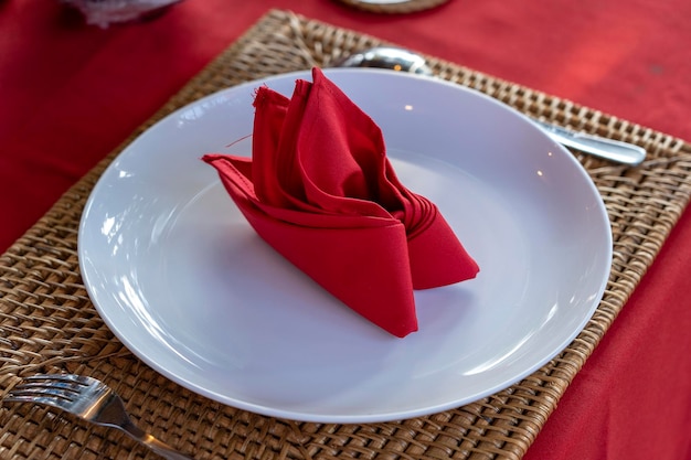 Elegante mesa con tenedor, cuchara, plato blanco y servilleta roja en el restaurante. Bonita mesa de comedor con cubiertos y servilletas arreglados.