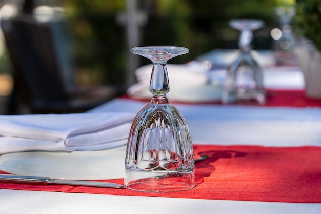 Elegante mesa con tenedor, cuchillo, copa de vino, plato blanco y servilleta roja en el restaurante. Bonito juego de mesa con cubiertos y servilletas para la cena.