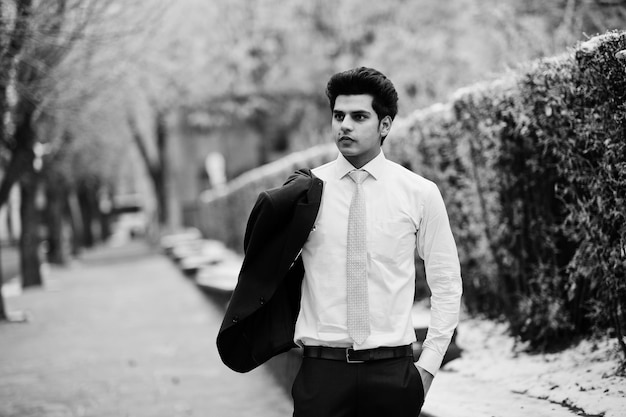 Elegante modelo de hombre macho indio con traje y corbata rosa posado en el día de invierno