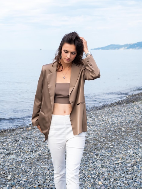 Foto una elegante modelo de moda camina por la orilla de la mar una hermosa joven alta en la playa en otoño