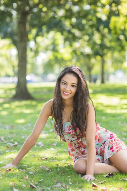 Elegante morena alegre sentada na grama