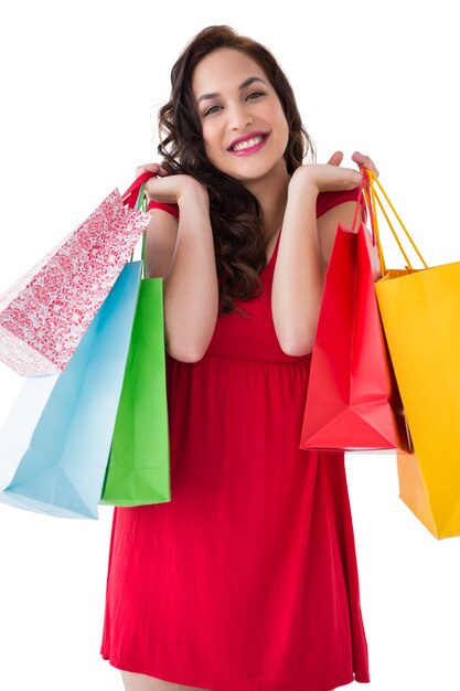 Elegante morena en vestido rojo con bolsas de compras