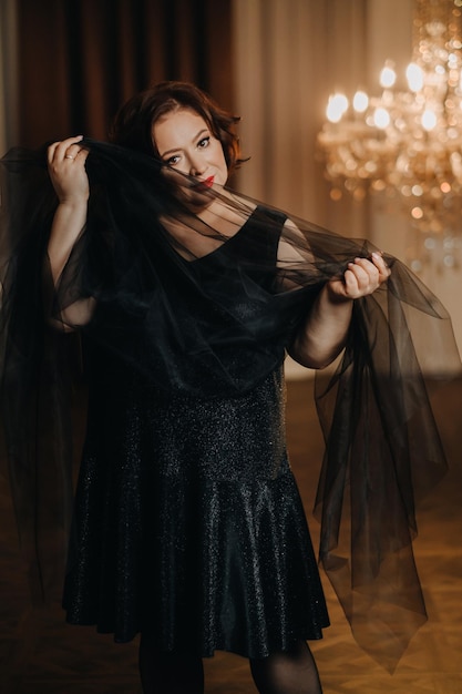 Una elegante mujer adulta con un vestido de cóctel negro posa en el interior Retrato de moda de una mujer