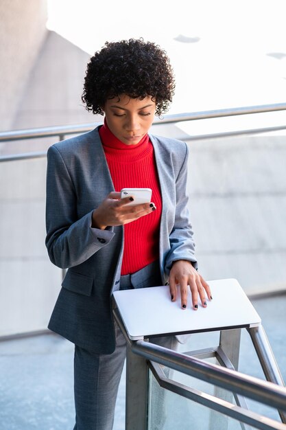 Una elegante mujer afroamericana que trabaja en su computadora portátil en un edificio de oficinas