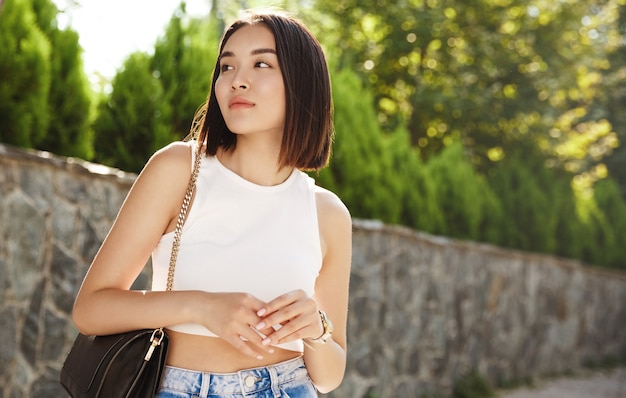 Elegante mujer asiática esperando a alguien en el parque