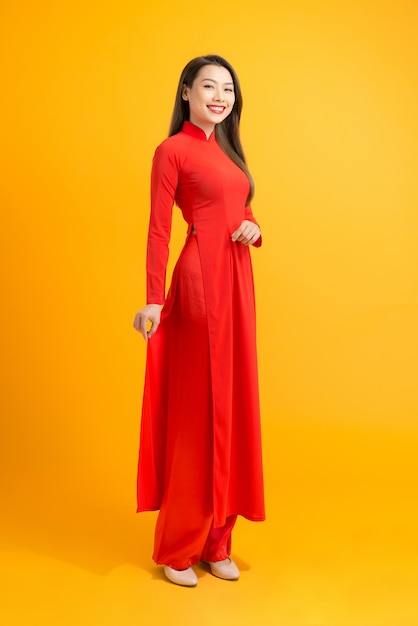 Elegante mujer asiática de pie sobre amarillo mientras usa la costumbre de Vietnam tradion Ao dai.