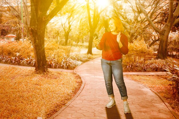 Foto una elegante mujer asiática con suéter de punto captura el momento con una selfie en un teléfono inteligente en el parque