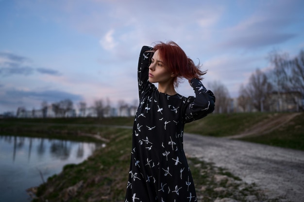 Elegante mujer atractiva de negro posa junto al lago