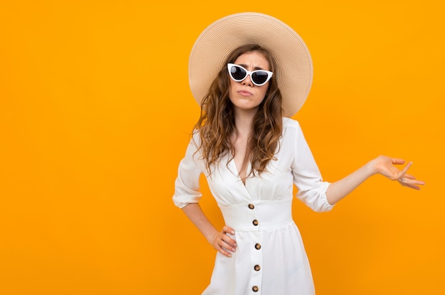 Elegante mujer de cabello castaño sobre un fondo amarillo con brazo extendido