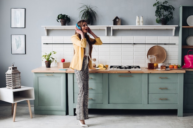 Foto elegante mujer con chaqueta amarilla y auriculares azules cantando