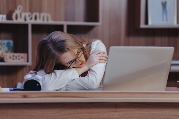 Elegante mujer duerme en el escritorio en una oficina moderna