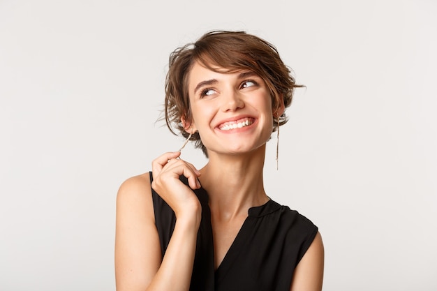 elegante mujer elegante sonriendo y mirando en la esquina superior izquierda