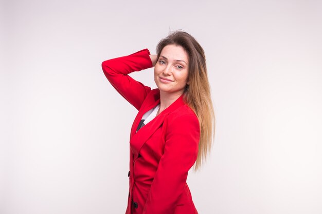 Elegante mujer europea en una chaqueta roja con la mano en el cabello,