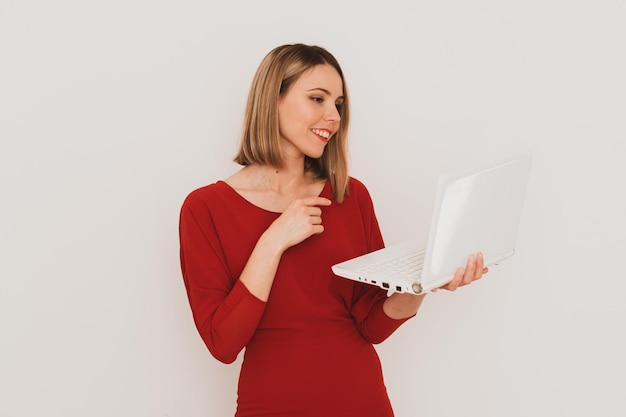 Elegante mujer europea vestida de rojo usando una laptop para comunicarse aislada de fondo blanco