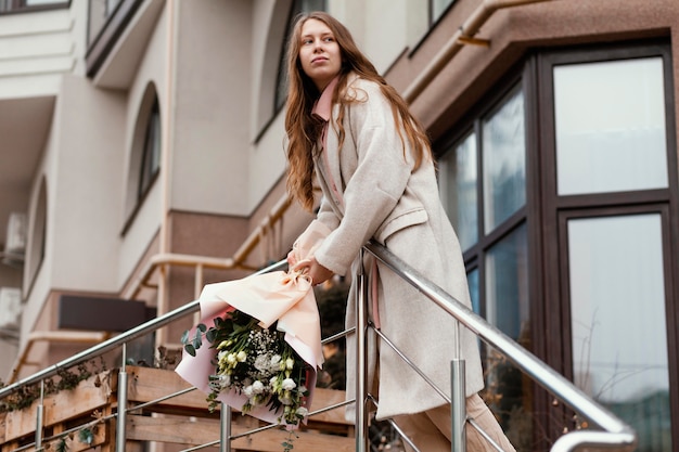 Foto elegante mujer feliz con ramo de flores en la ciudad