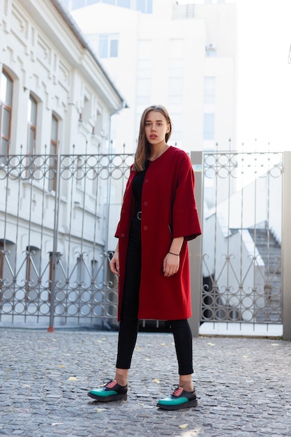 Elegante mujer hermosa caminando en la calle con abrigo rojo, tendencia de moda de otoño. Foto de otoño de moda. Moda femenina. Estilo de vida de la ciudad.