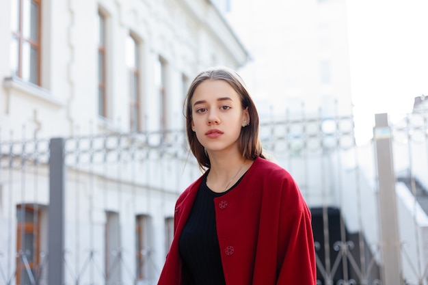 Elegante mujer hermosa caminando en la calle con abrigo rojo, tendencia de moda de otoño.