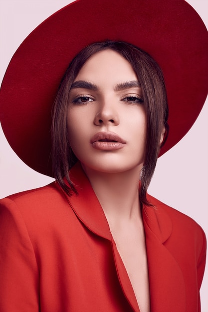 Elegante mujer hermosa en un traje rojo de moda y sombrero ancho