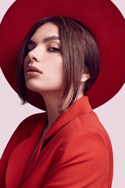 Elegante mujer hermosa en un traje rojo de moda y sombrero ancho