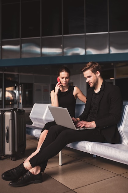 Elegante mujer y hombre trabajando en un portátil en el aeropuerto