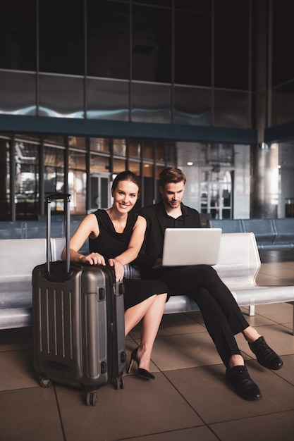 Elegante mujer y hombre trabajando en un portátil en el aeropuerto