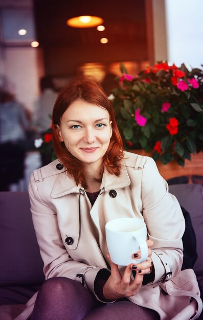 Elegante mujer joven sentada en el café con una taza de té. Otoño. Budapest, Hungría, Europa.