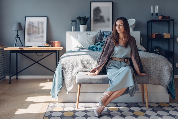 Elegante mujer joven sentada en el dormitorio. Interior de la casa