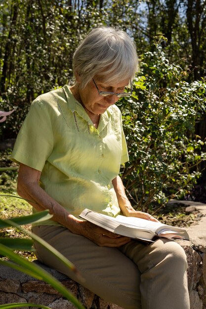 Elegante mujer madura leyendo un libro en el jardín