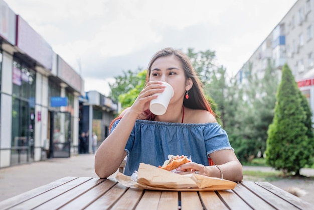 Elegante mujer milenaria comiendo hamburguesas en un café callejero en verano