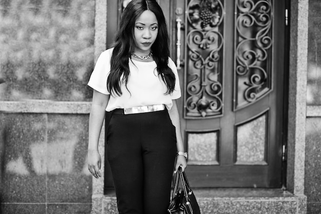 Elegante mujer de negocios afroamericana con bolso en las calles de la ciudad