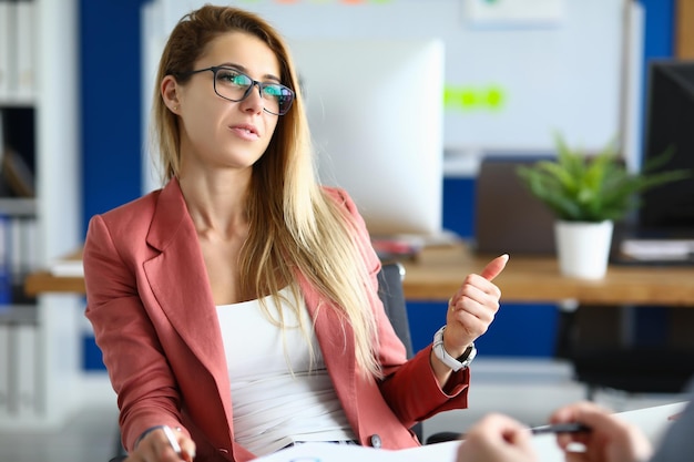 Foto elegante mujer de negocios con gafas hablando con un colega en el lugar de trabajo