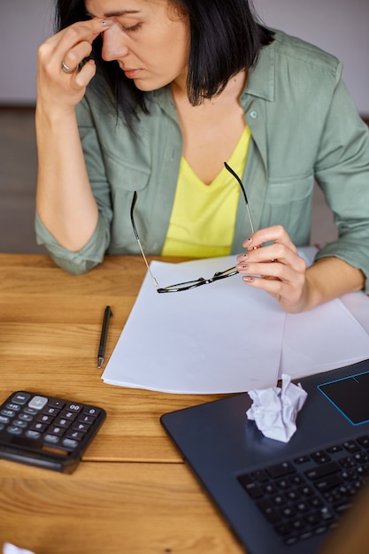 Foto elegante mujer de negocios morena se quita las gafas que trabajan en el lugar de trabajo moderno