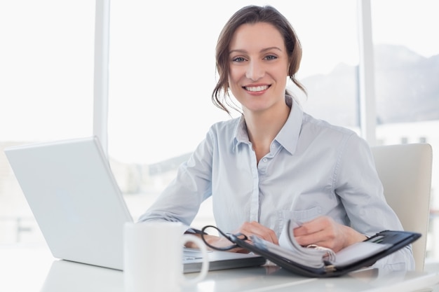 Foto elegante mujer de negocios con ordenador portátil y diario en la oficina