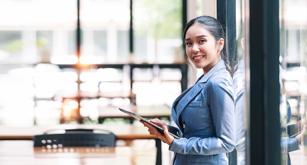 Elegante mujer de negocios de pie en la oficina con tableta digital