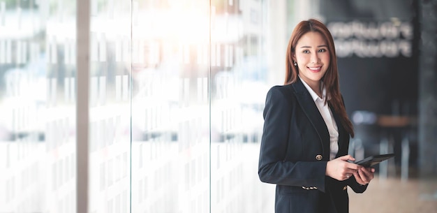 Elegante mujer de negocios de pie en la oficina con tableta digital