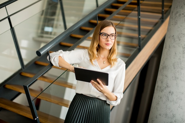 Elegante mujer de negocios de pie en la oficina con tableta digital