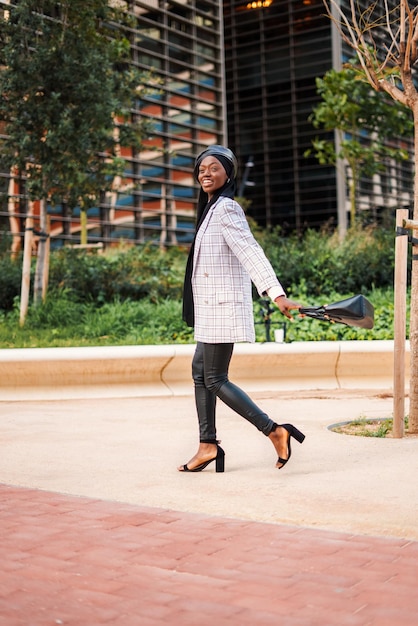 Elegante mujer negra disfrutando de un agradable paseo por el parque de la ciudad