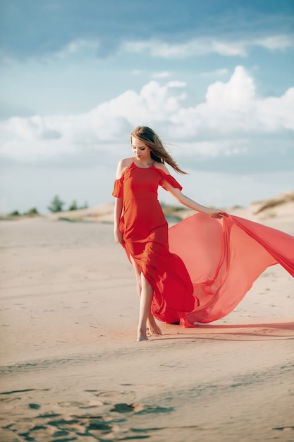 elegante mujer posando en la playa con vestido rojo